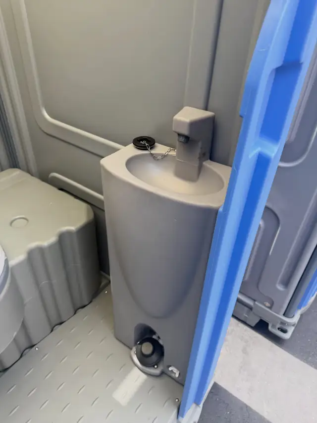 Foot-pump sink inside a flushing porta potty