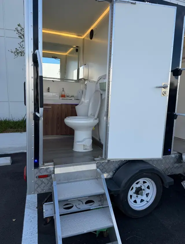 Restroom trailer with door open showing toilet and vanity