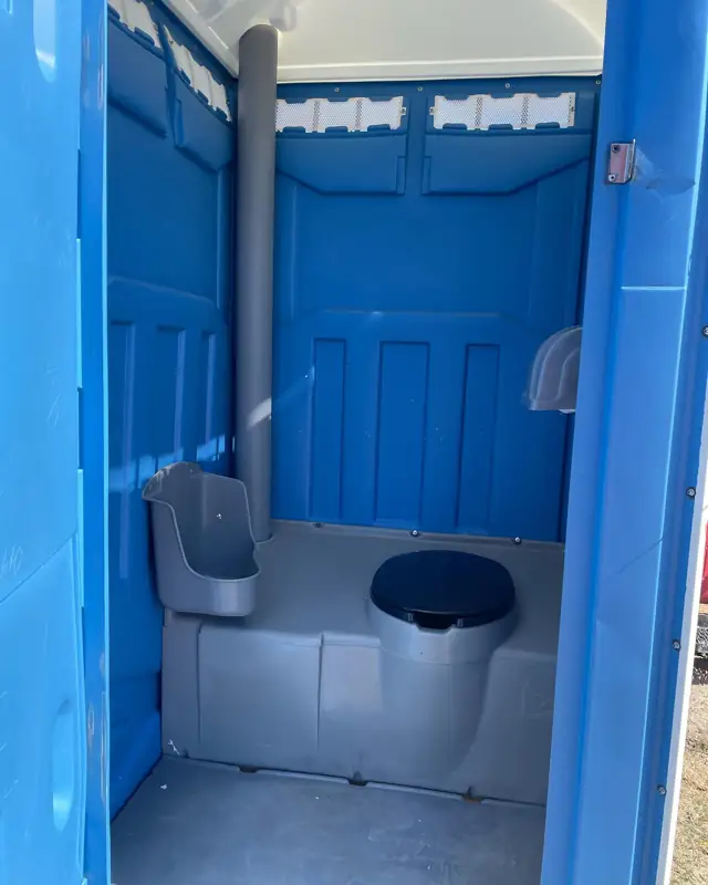 Inside a standard porta potty showing toilet and urinal